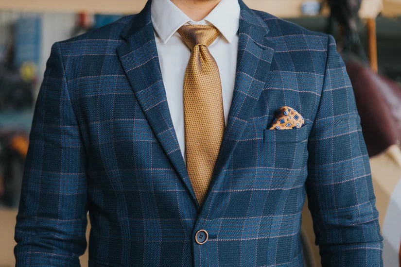 A close up of a bespoke blue suit and gold tie - Cultivate Unforgettable Client Experiences with Pearce Bespoke 
