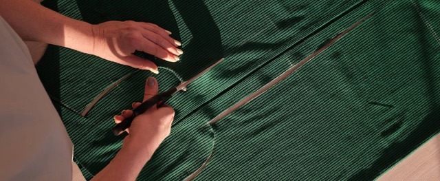 A woman cutting a panel out of green fabric that will be used by Pearce Bespoke.
