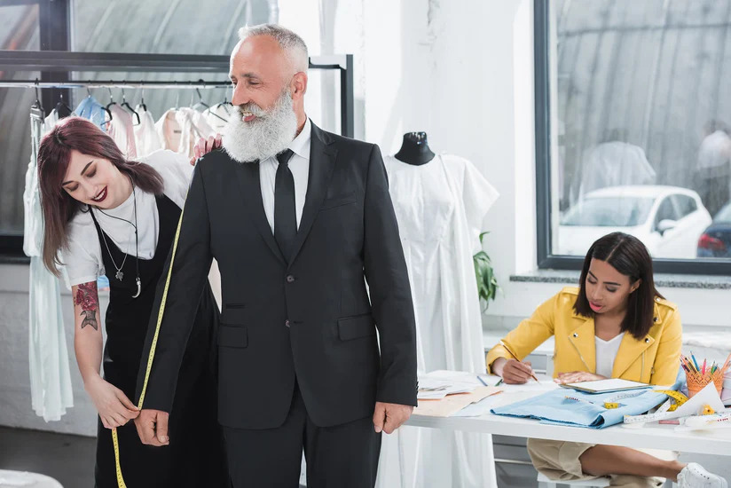 An image of a woman tailor helping a customer take measurements - create the ultimate customer experience with Pearce Bespoke.