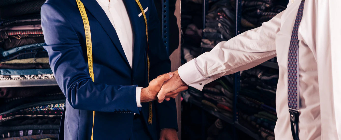 An image of a tailor and customer shaking hands - learn how you can drive community engagement as a Pearce Bespoke owner.
