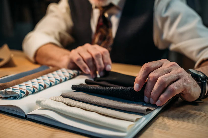 A tailor browsing through fabrics - learn why fabric selection is important for your tailoring franchise.