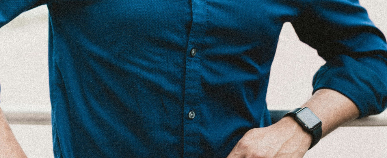 A man wearing a darker blue shirt with buttons down the middle - learn how you choose the perfect buttons for your shirts with Pearce Bespoke Greater Syracuse.