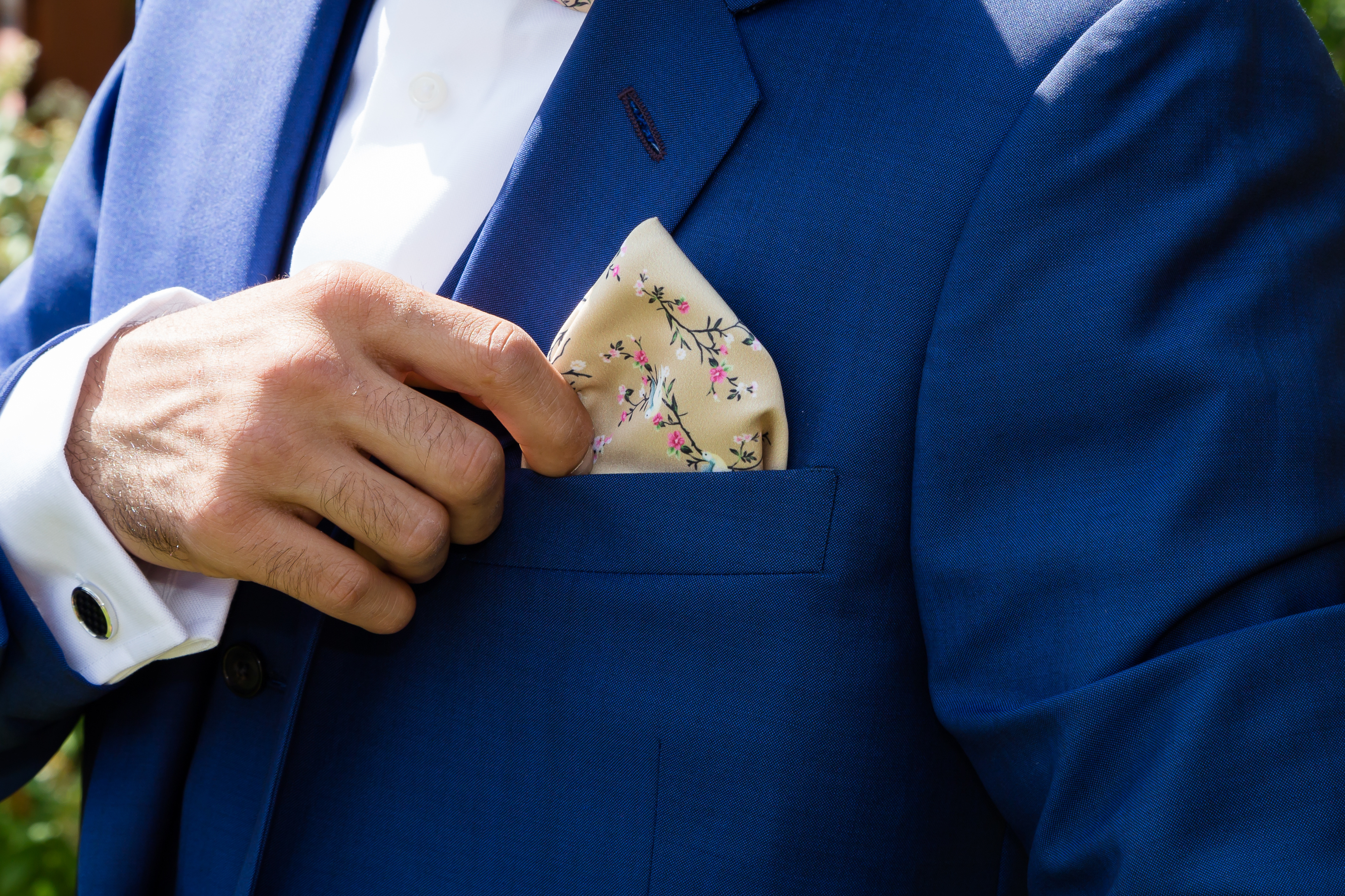 An image of a person pulling out their suit pocket square - find the perfect one for your suit with Pearce Bespoke.