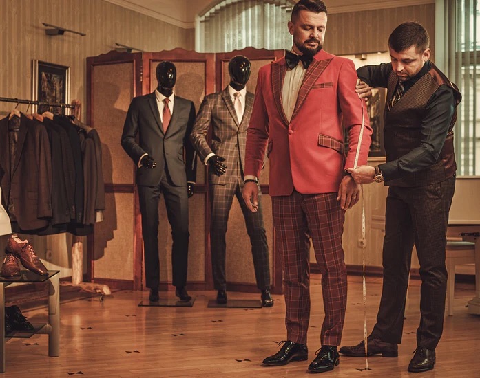 A man in a read a plaid suit that is being altered -  The Power of Brand Identity in Bespoke Suit Franchising Success with Pearce Bespoke 