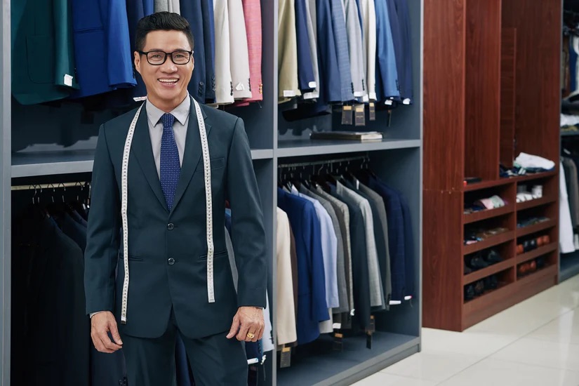 A man in a bespoke suit with a measuring tape around his neck -  Sartorial Excellence in Entrepreneurship: Building a Legacy with Pearce Bespoke 