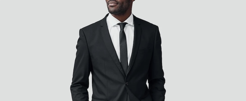 A man wearing a black suit with a stylish white shirt made by Pearce Bespoke.