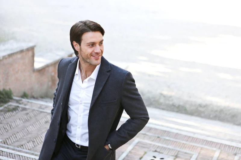 A man wearing a black, well-tailored suit with the perfect fabric for warm weather.