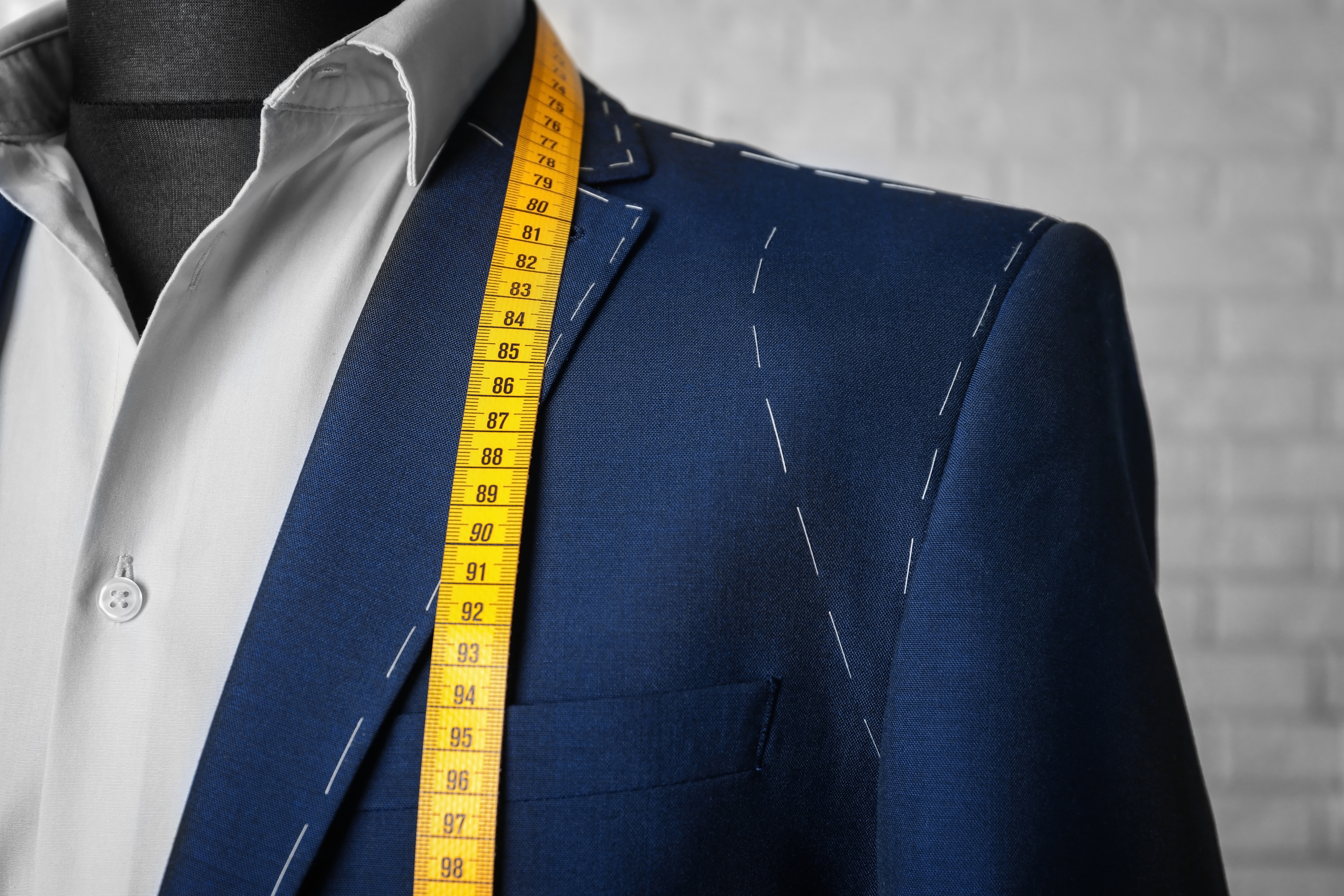 An image of a suit with stitching around the edges and measuring tools - Pearce Bespoke.