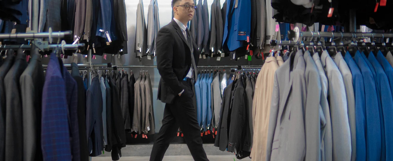 An image of a man walking through a store with suit racks - understand everything you need to know about suit vents.