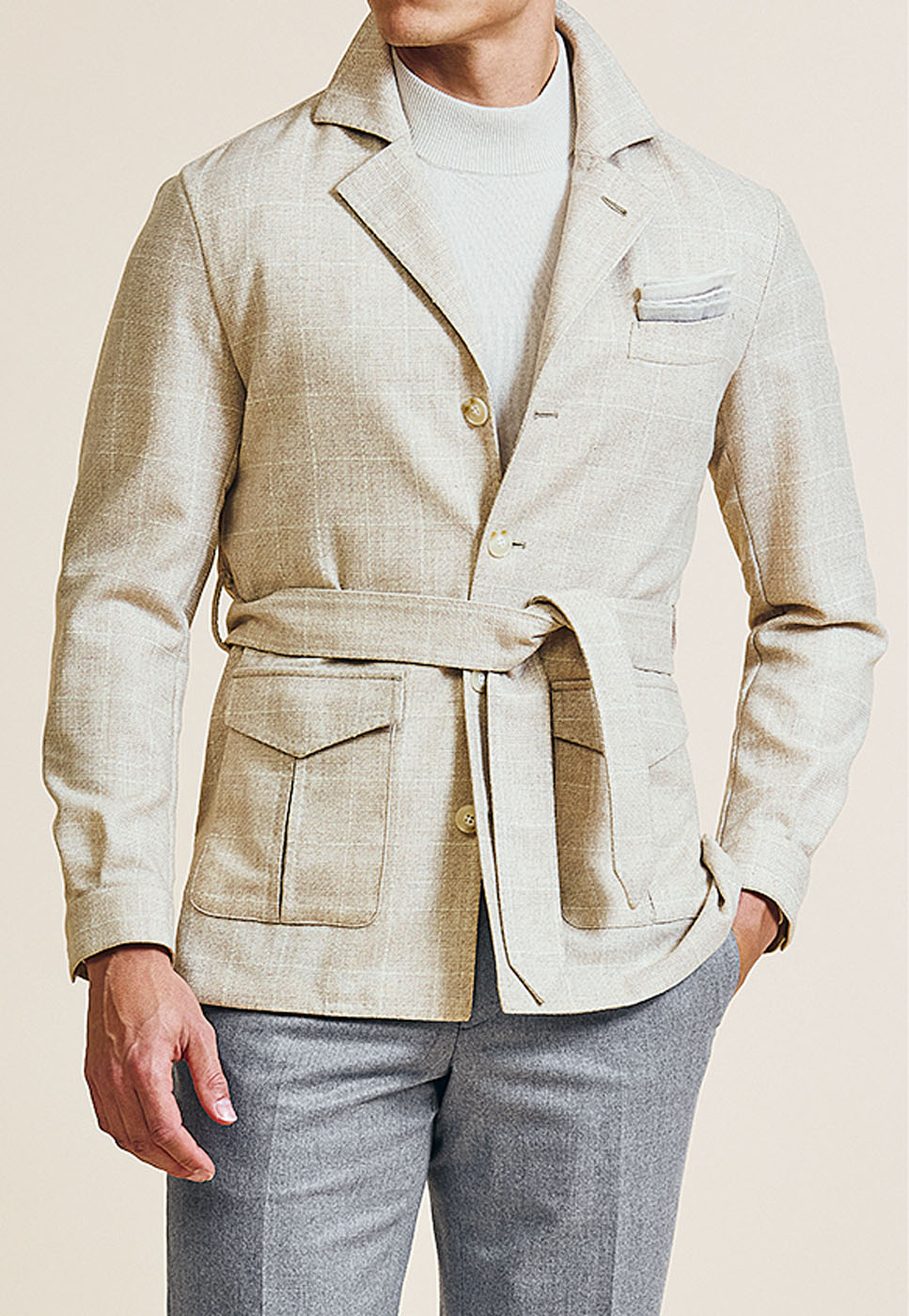 A close-up shot of a male model styling a Pearce Bespoke Greater Syracuse custom cream-colored coat.