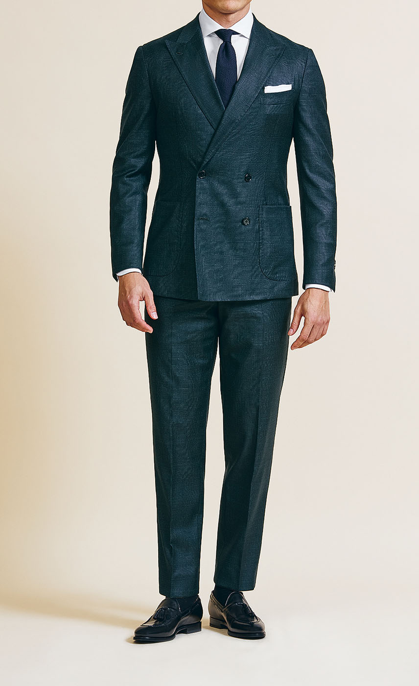 A male model styling a Pearce Bespoke Greater Syracuse custom suit in a deep green color with a dark tie.