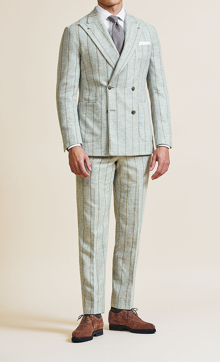 A male model styling a Pearce Bespoke Greater Syracuse custom suit in a very light green color with dark pinstripes.