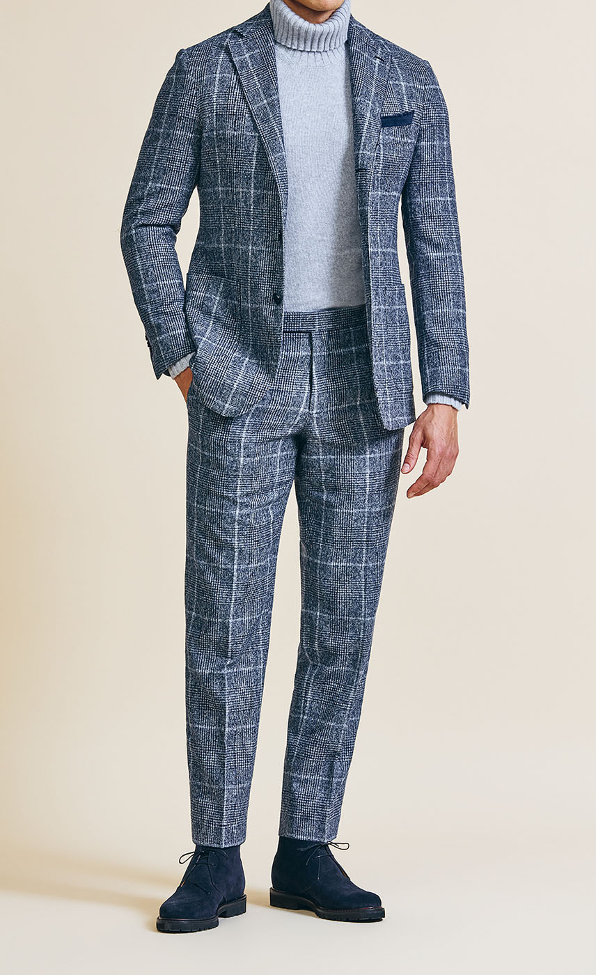 A male model styling a Pearce Bespoke Greater Syracuse custom suit with an open jacket in a blue-gray color.