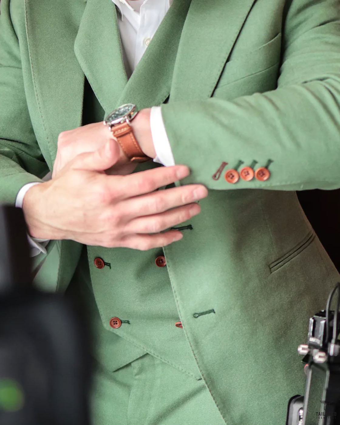 A green custom suit with brown buttons, choose Pearce Bespoke for a custom clothing franchise.