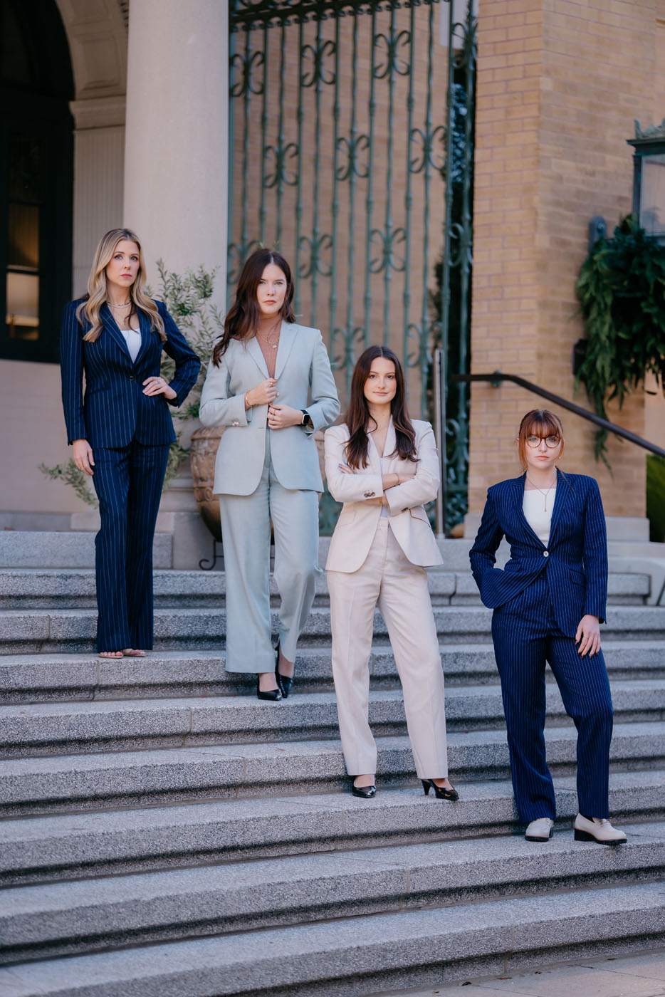 A group of 4 women on stone steps - for custom real estate agent suits, reach out to Pearce Bespoke today.